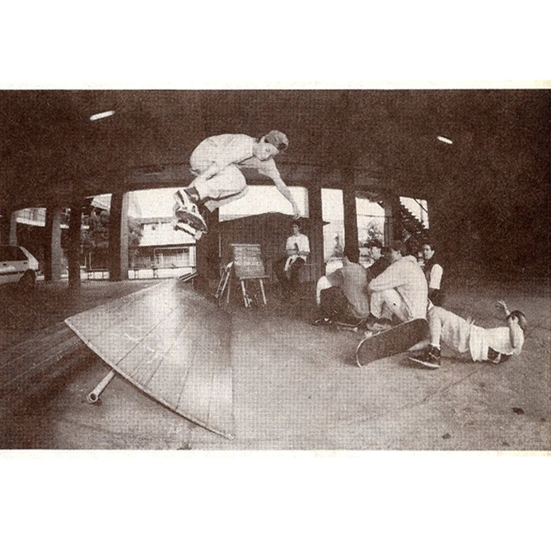 Jason performing an Ollie Melon Grab on a piece of wood (perhaps a door) made into a ramp,
  as five friends look on.