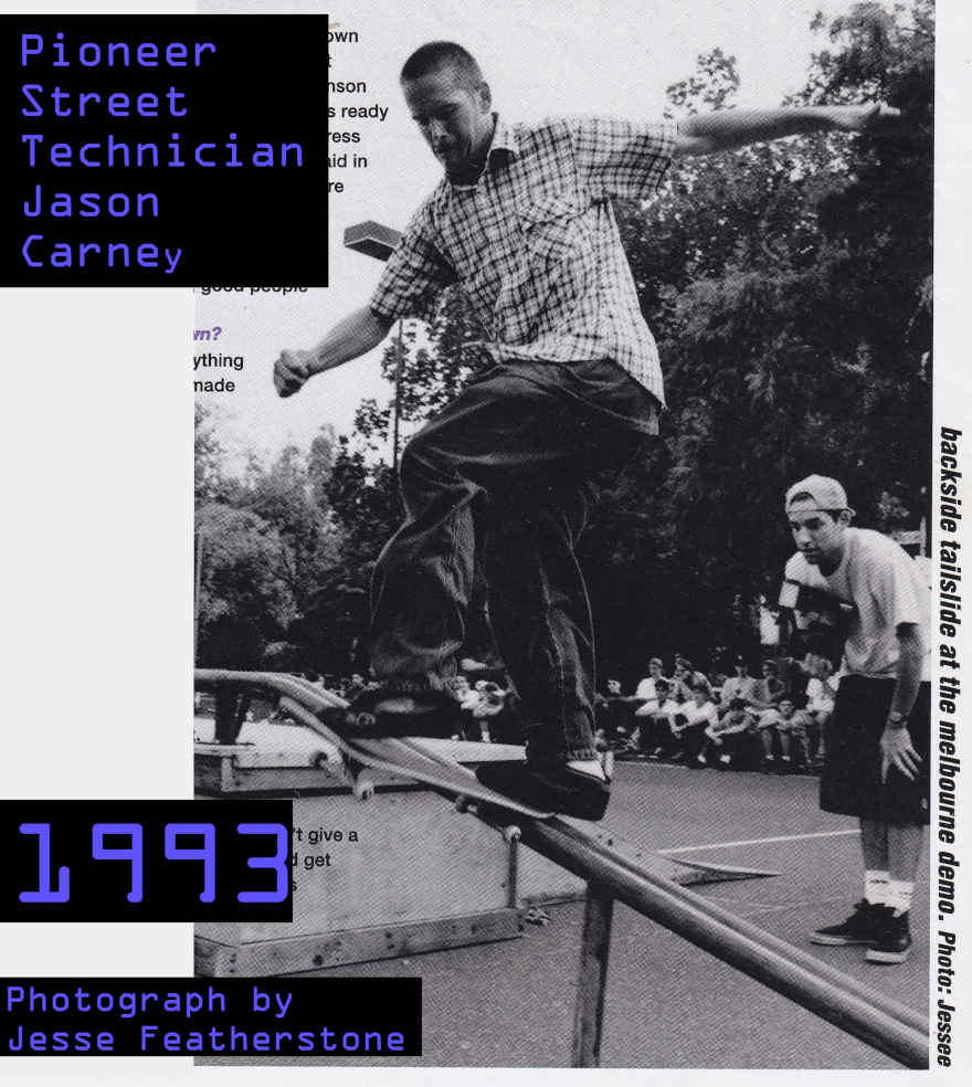 Black and white photo of Jason Carney doing a backside tailslide (or possibly frontside bluntsie transfer)
    on a handrail at Prahran Basketball Courts. The handrail is part of a platform that was used on the day for a skate demonstration.
    David Walsh is in the background holding a camera and wearing cap backwards. There are many spectators, sitting watching Jason on the edge of the court.